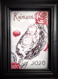 a black frame with an image of a baby in a nest